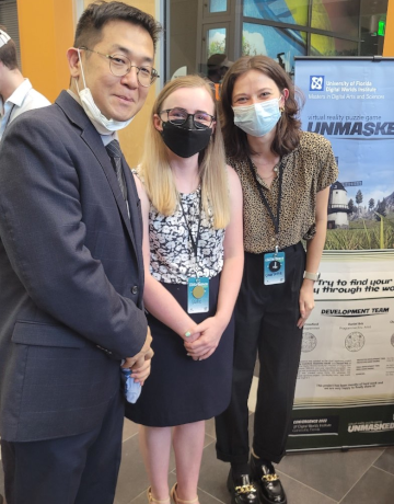 Seung Hyuk Jang (professor), Sadie Crawford, and Charlotte Atwill (left to right) standing next to an 'Unmasked' banner at University of Florida's 2022 Convergence event